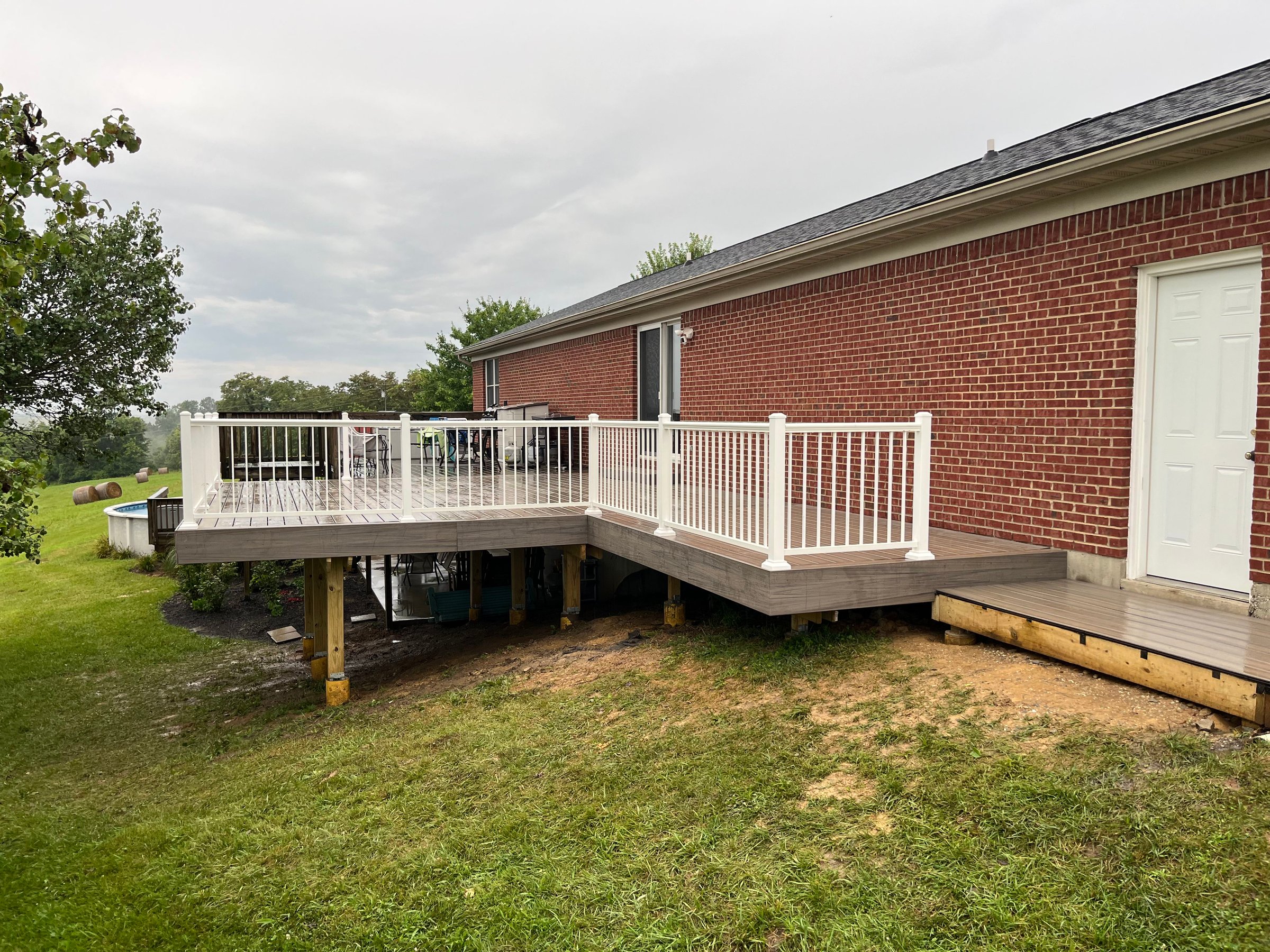 Finished composite deck with white railing beside a brick home